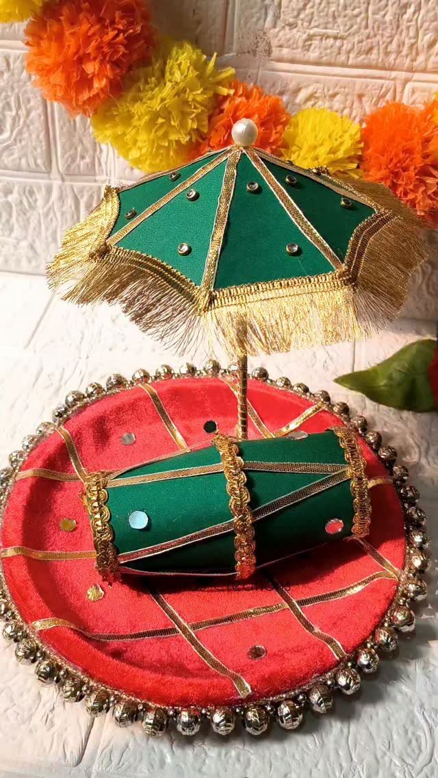 Decorative mehndi platter with a small green umbrella and dhol drum on red velvet.
