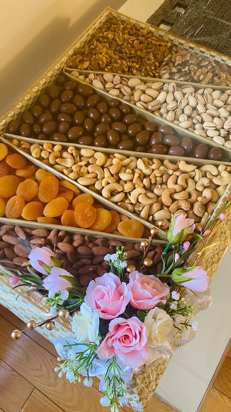Gold snack tray filled with dried fruits and nuts, decorated with pink roses.