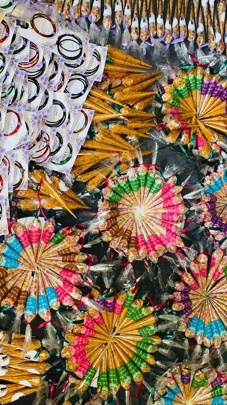 Colorful fabric-wrapped henna cones arranged in circular patterns alongside plain cones and bangles.
