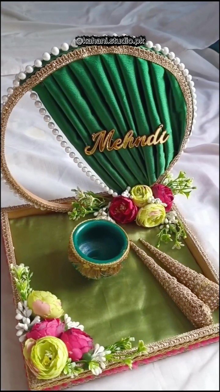 Green mehndi platter decorated with pink and yellow faux flowers, pearls, and gold trim.