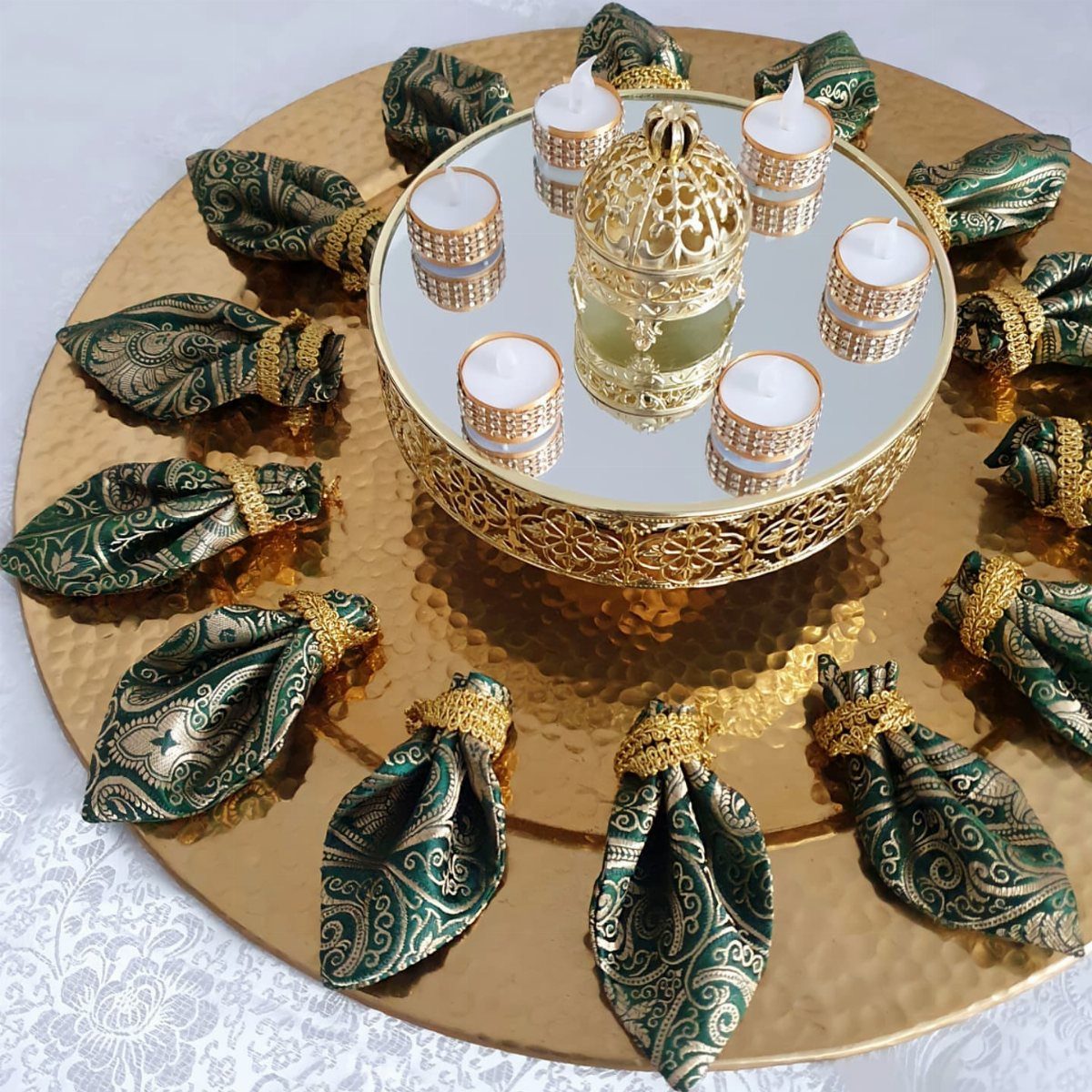 Gold hammered platter with green patterned henna cones and a mirrored candle stand.