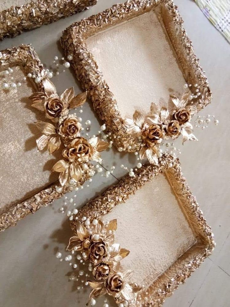 Gold rectangular trays decorated with metallic roses and small white pearls.
