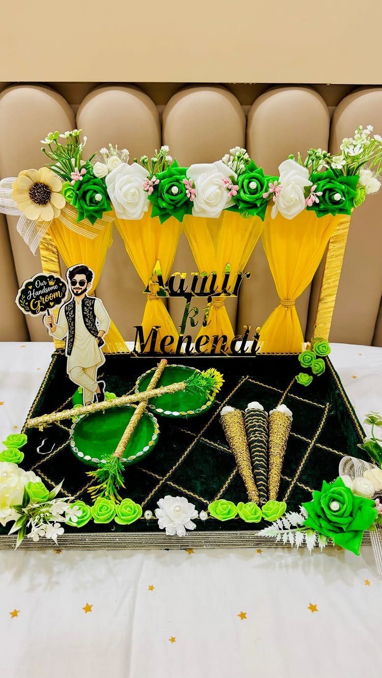 Groom's mehndi platter with black velvet base, gold cones, and yellow fabric curtains.