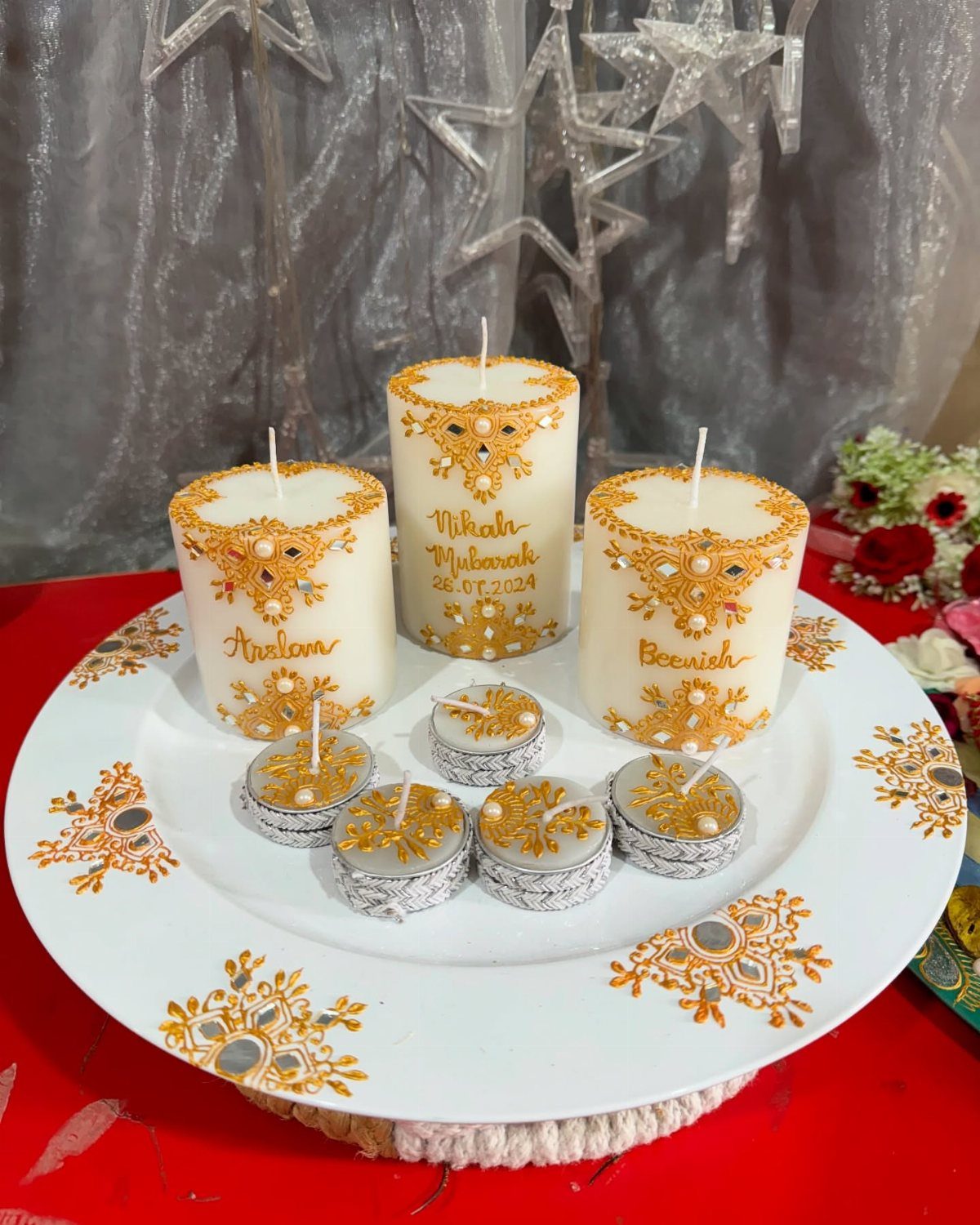 White decorated platter with gold mirrored pillar candles and tea lights on red fabric.