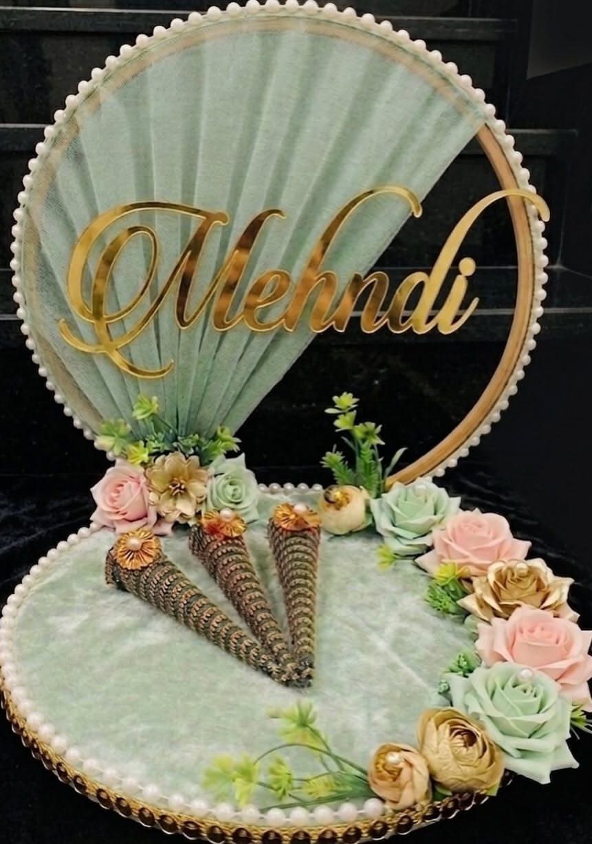 Mint green velvet mehndi platter with pastel roses and gold script backdrop.