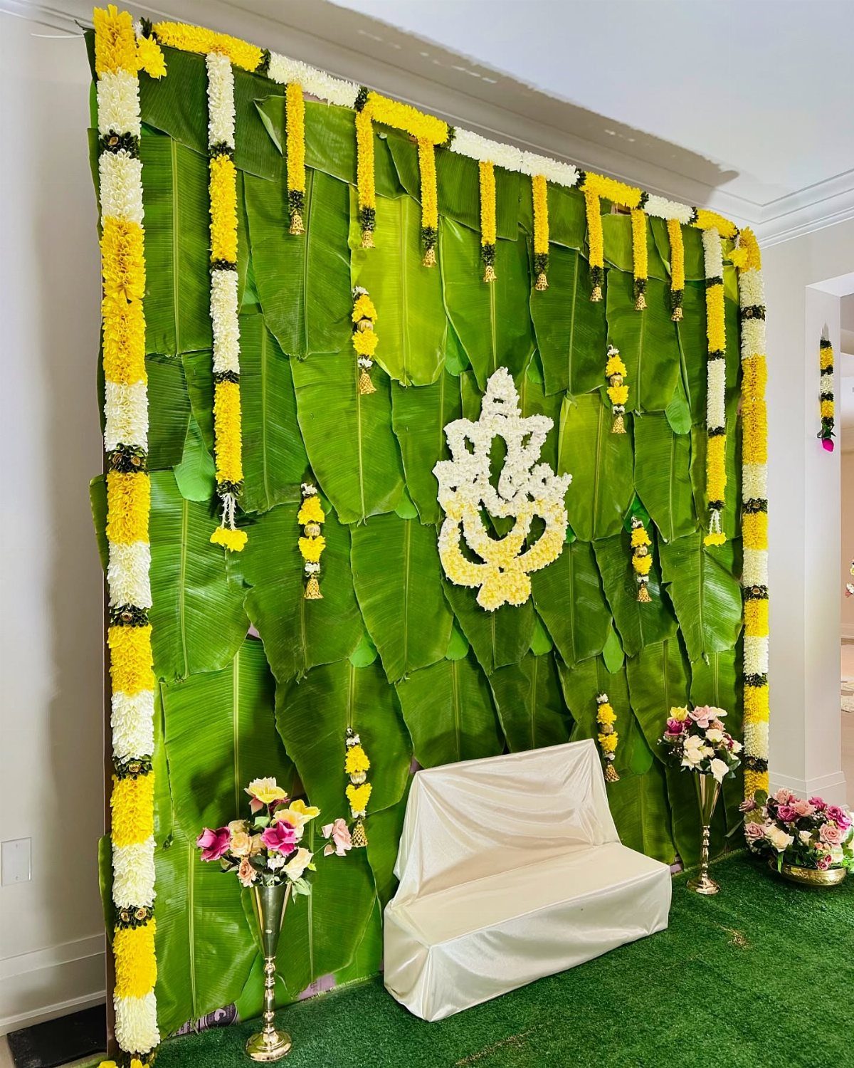 15 Seemantham Decoration Ideas for a Joyful Baby Shower 2 Banana leaves backdrop with marigold garlands and a white floral Ganesha motif.