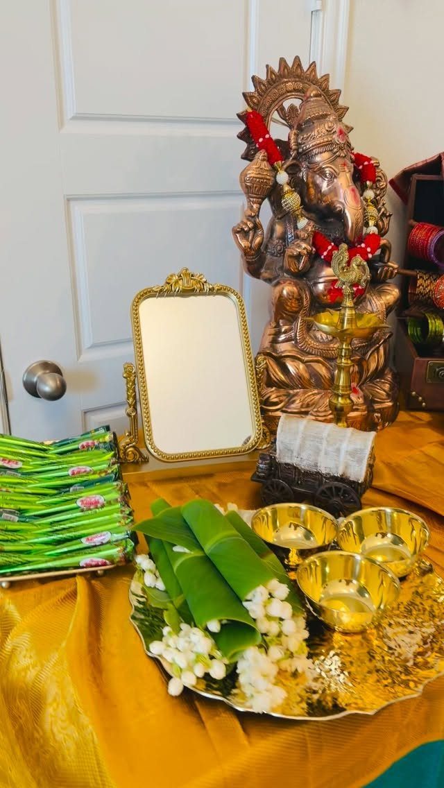 15 Seemantham Decoration Ideas for a Joyful Baby Shower 16 Ganesha statue and gold bowls with flowers on a gold cloth covered table.
