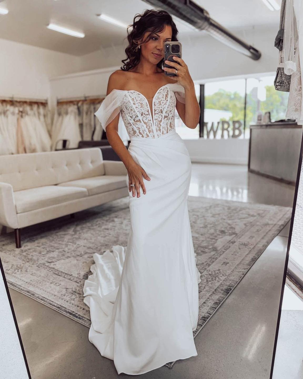 Woman in a white wedding dress with a plunging sweetheart neckline and off-the-shoulder sleeves.