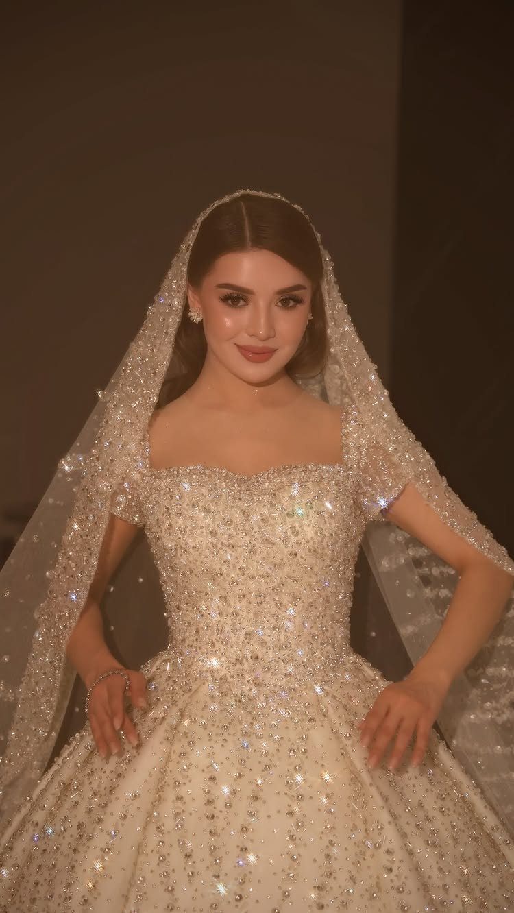 Woman in a sparkling white sweetheart wedding gown with a glittery veil.