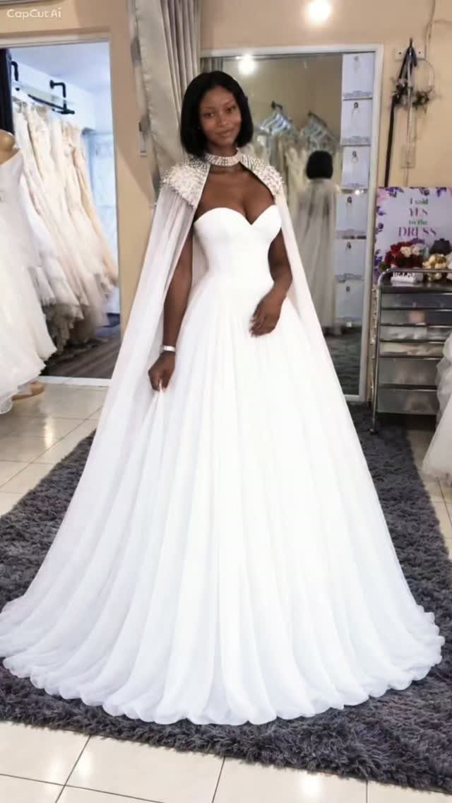 Woman in a white sweetheart wedding dress with a full skirt and bridal cape.