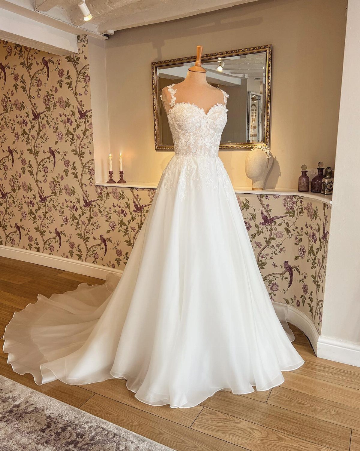 White wedding dress with sweetheart neckline and floral lace bodice on a mannequin.