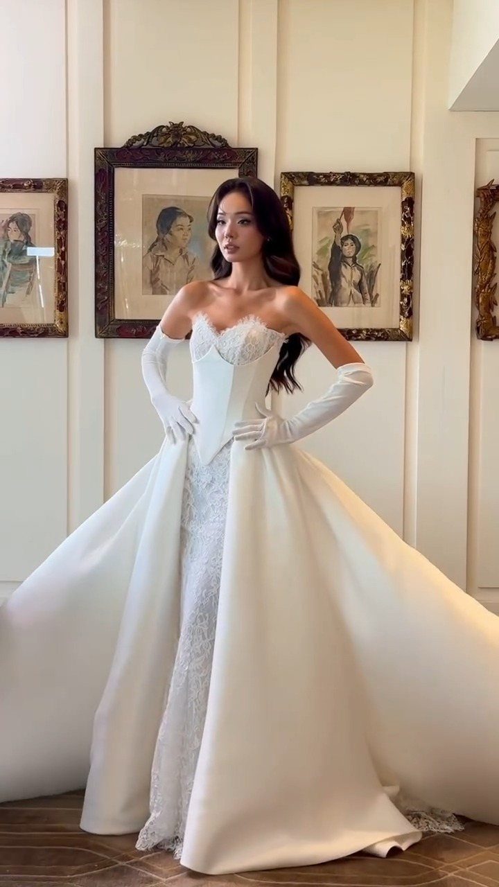 Woman in a white sweetheart wedding dress with a voluminous removable overskirt and gloves.