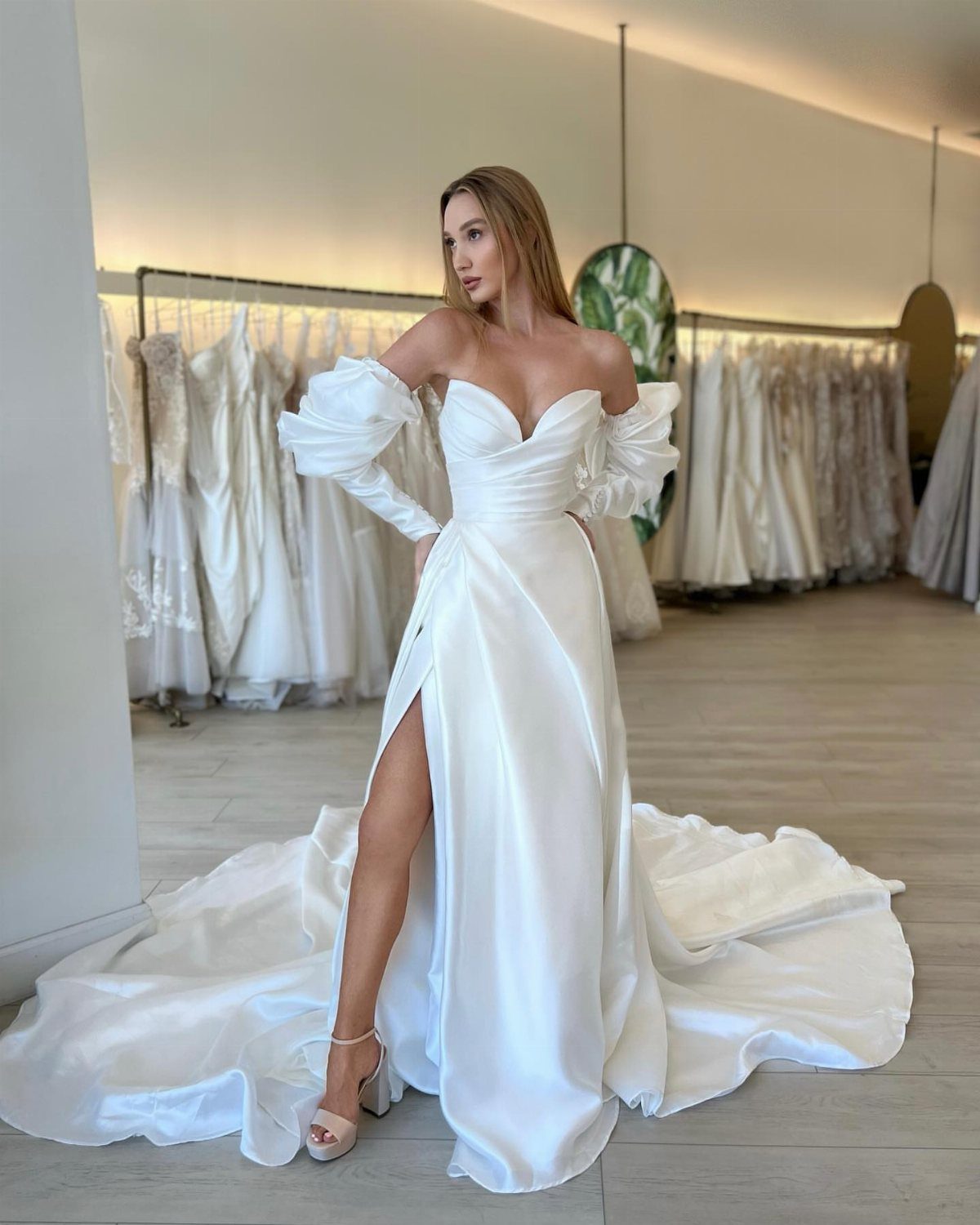Woman in a white satin sweetheart wedding dress with a high leg slit.