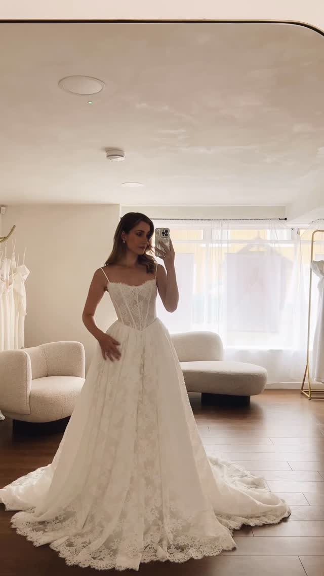 Woman in a white lace wedding dress with a sweetheart neckline taking a selfie