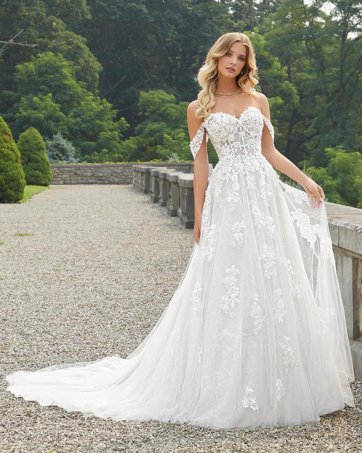 Woman in a white tulle wedding dress with sweetheart neckline and floral lace details.