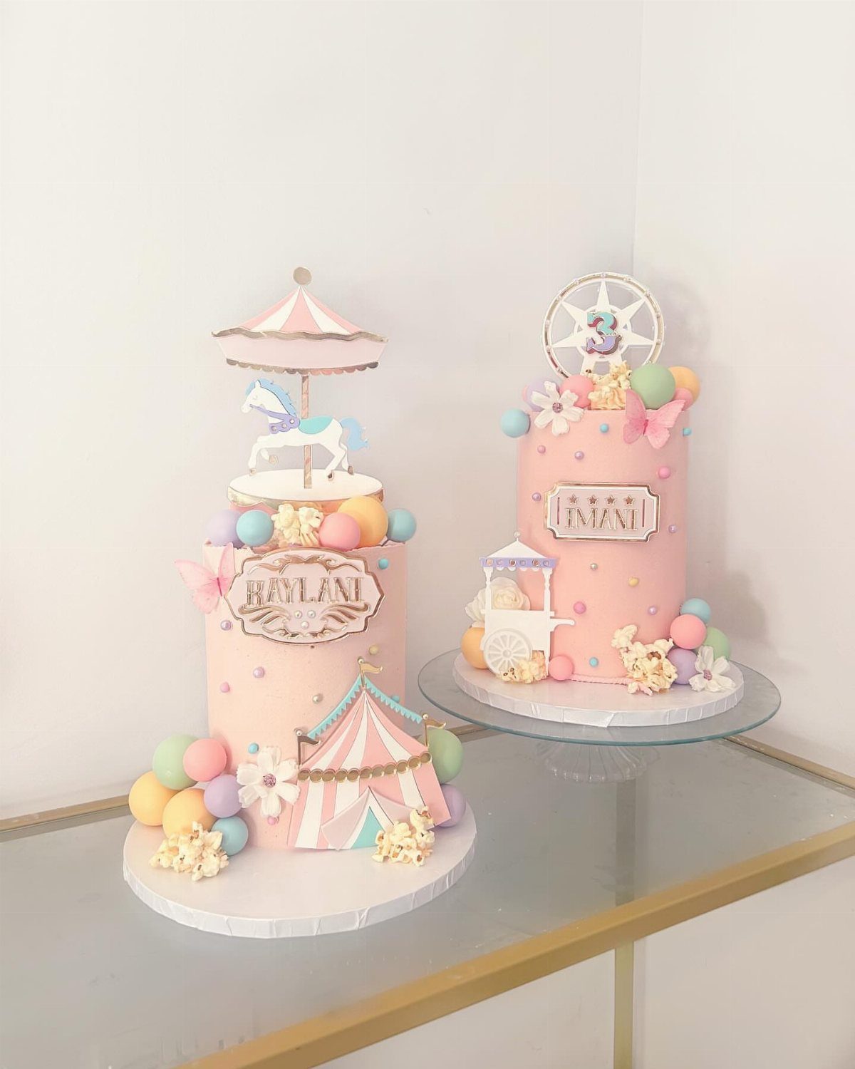 Two pink carnival themed birthday cakes with carousel and Ferris wheel toppers.