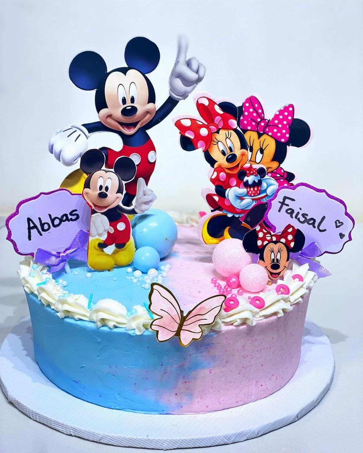 Blue and pink split birthday cake with Mickey and Minnie Mouse character toppers.