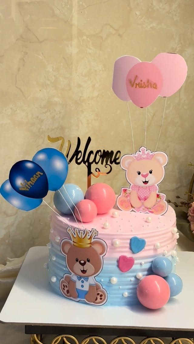 Pink and blue split birthday cake with bear toppers and balloon decorations.