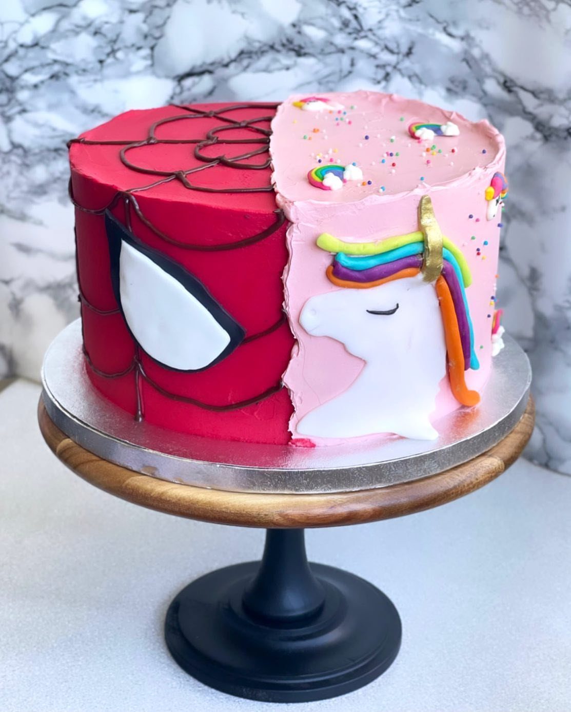 Split birthday cake featuring a red Spider-Man side and a pink unicorn side.