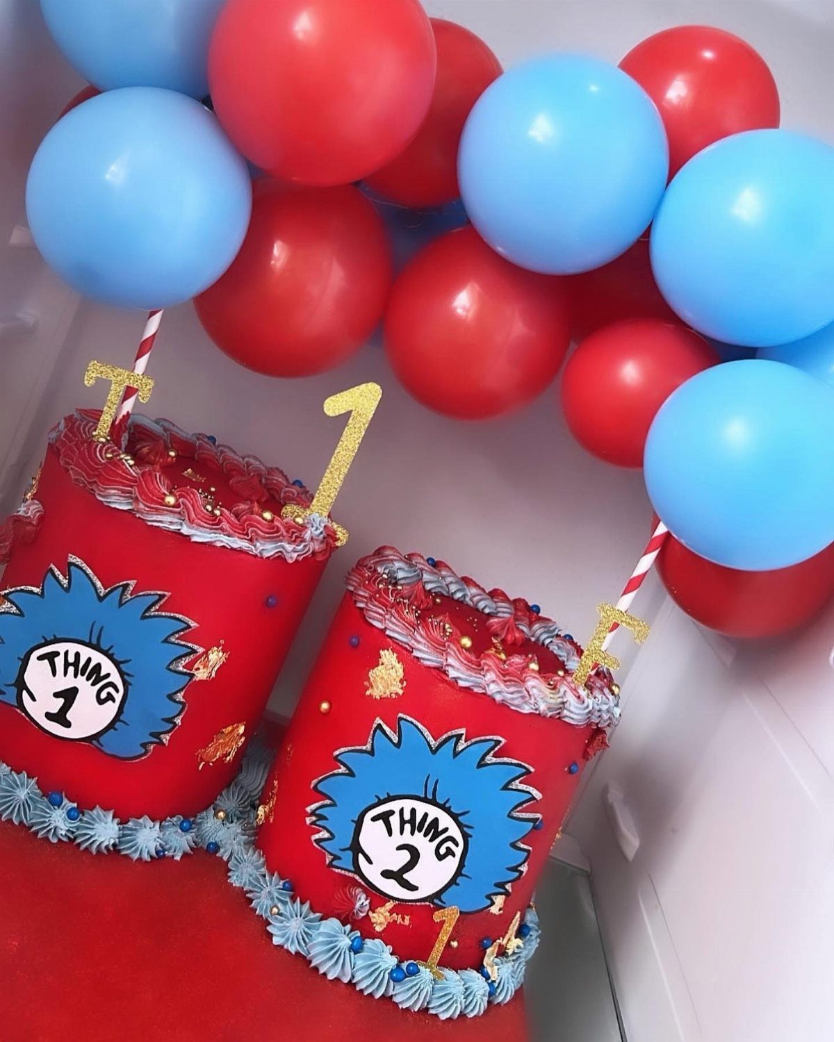 Two red Thing One and Thing Two cakes with blue and red balloons.