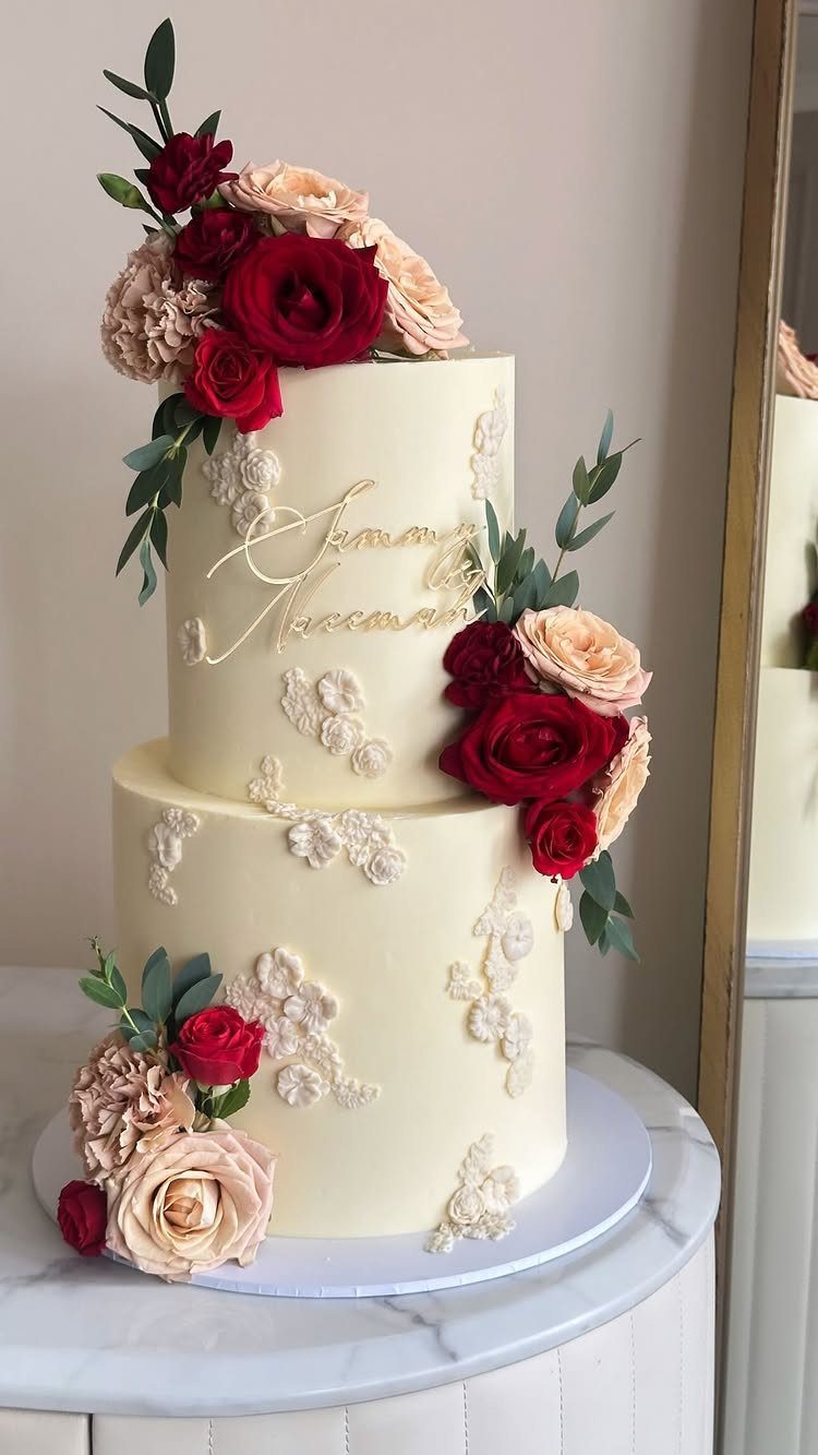 37 Wedding Cakes with Flowers to Inspire Your Design 3 Two-tier white cake with red and peach rose floral toppers and lace details.