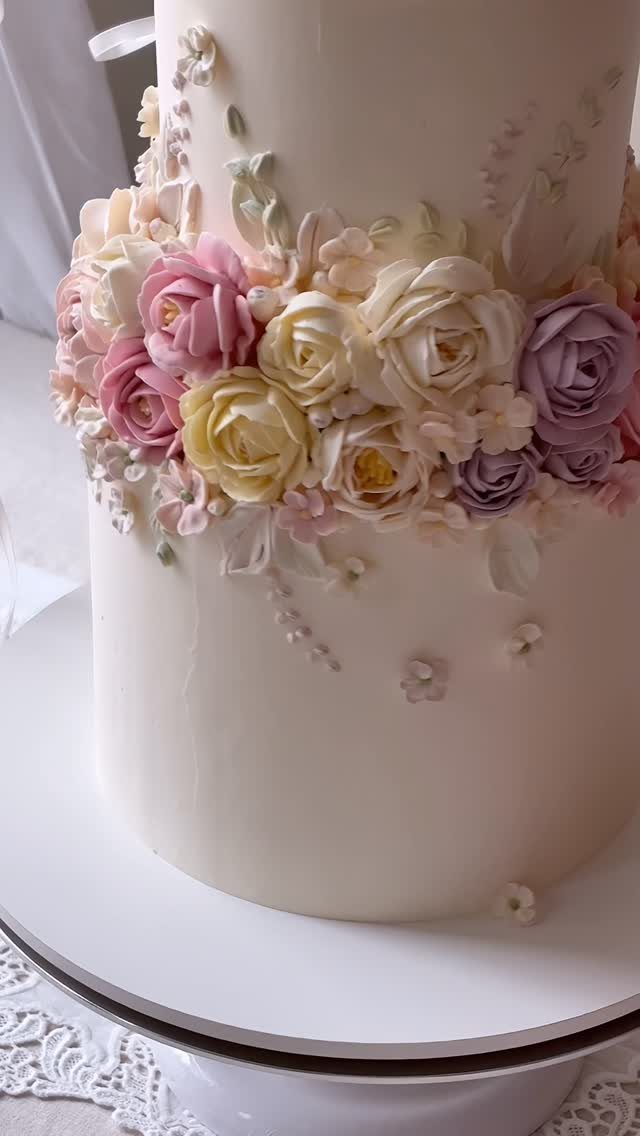 37 Wedding Cakes with Flowers to Inspire Your Design 32 White tiered wedding cake adorned with pink, yellow, and purple frosting roses.