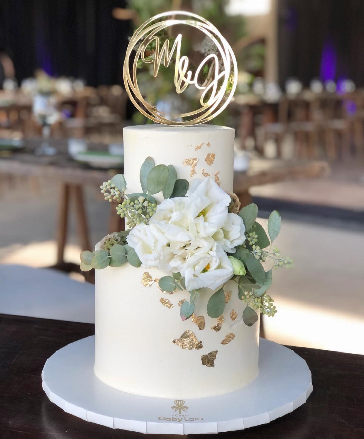 37 Wedding Cakes with Flowers to Inspire Your Design 5 Two-tier white wedding cake with white flowers, eucalyptus greenery, and gold leaf accents.