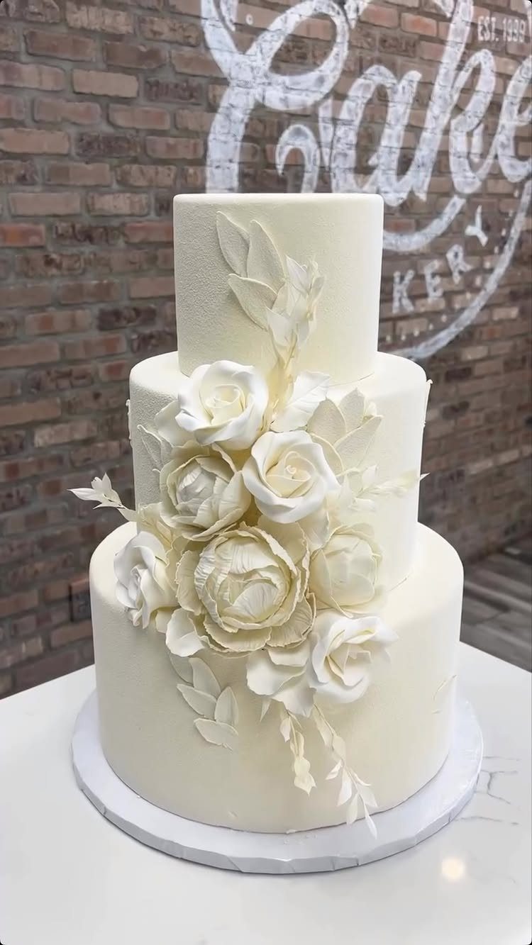 37 Wedding Cakes with Flowers to Inspire Your Design 6 Three-tier white wedding cake adorned with large sculpted white sugar roses and leaves.
