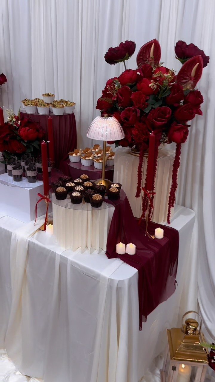 Burgundy and white wedding dessert table with red roses and chocolate cupcakes