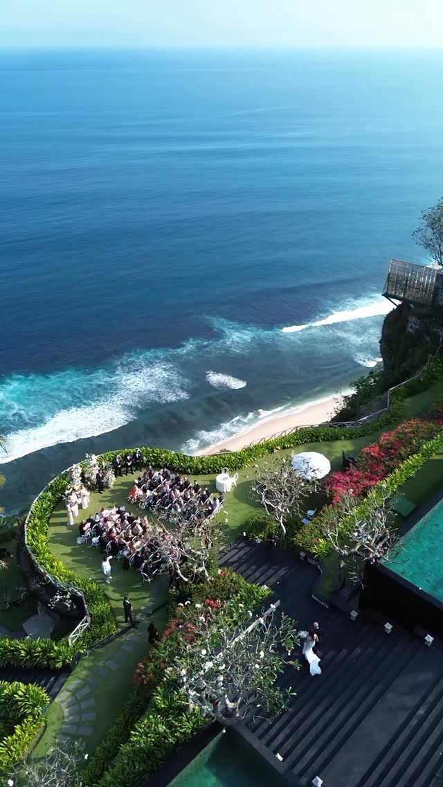 Small wedding ceremony on a green cliff overlooking a blue ocean and beach.
