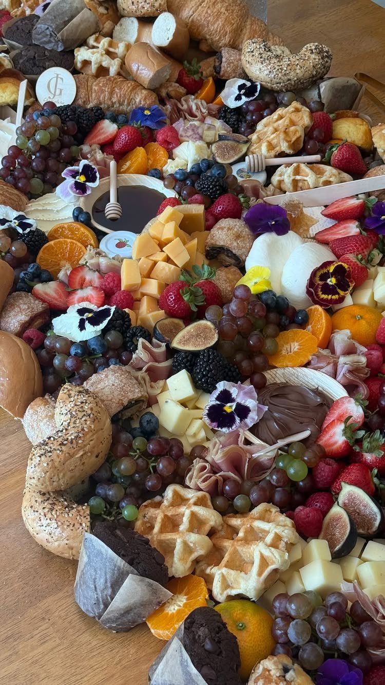 Breakfast grazing table with waffles, bagels, fresh fruits, cheeses, and edible flowers.