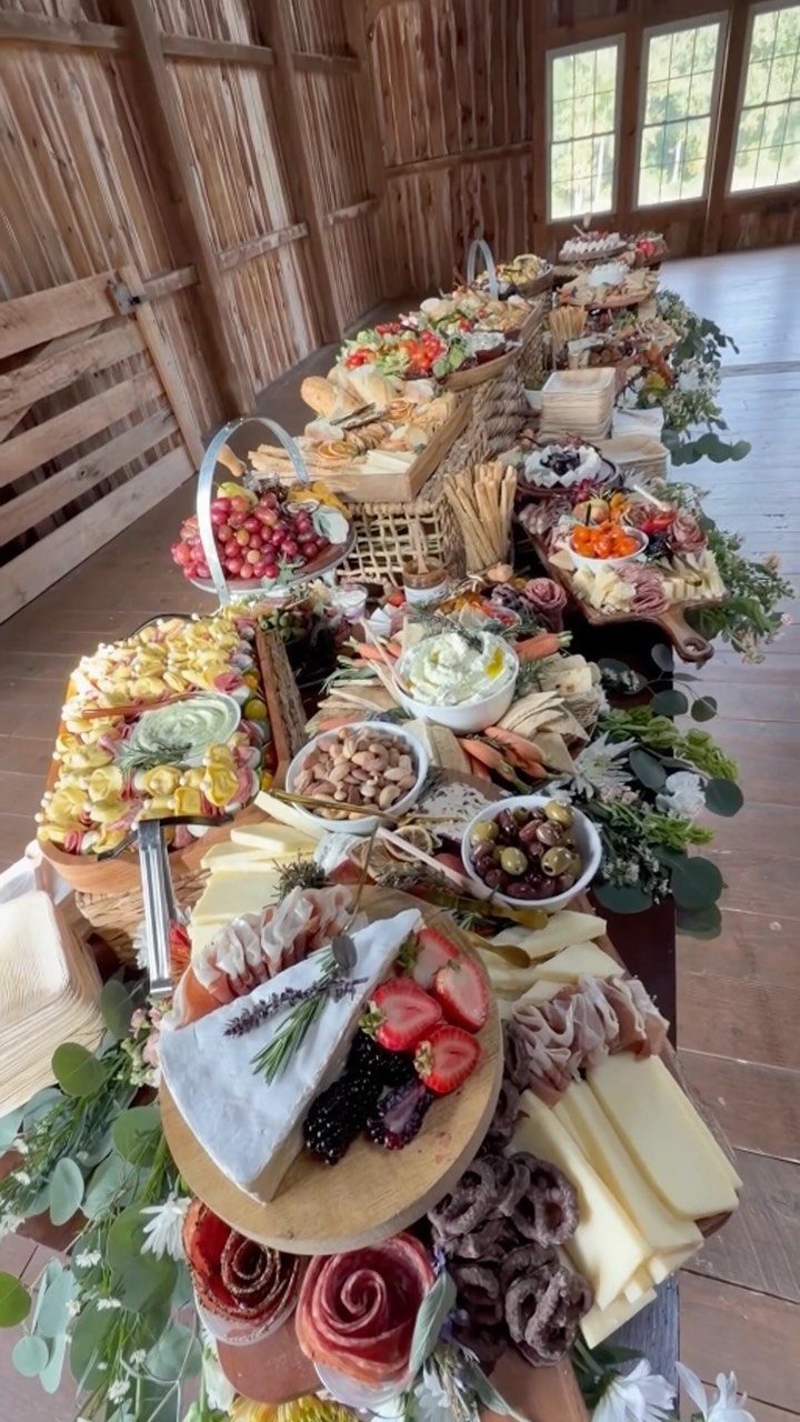 Lavish charcuterie spread on a wooden table decorated with fresh green eucalyptus leaves.