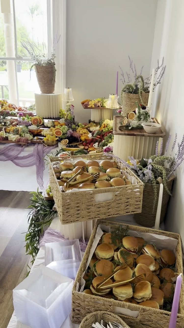 Wicker baskets of sliders and a fruit grazing table with floral decorations