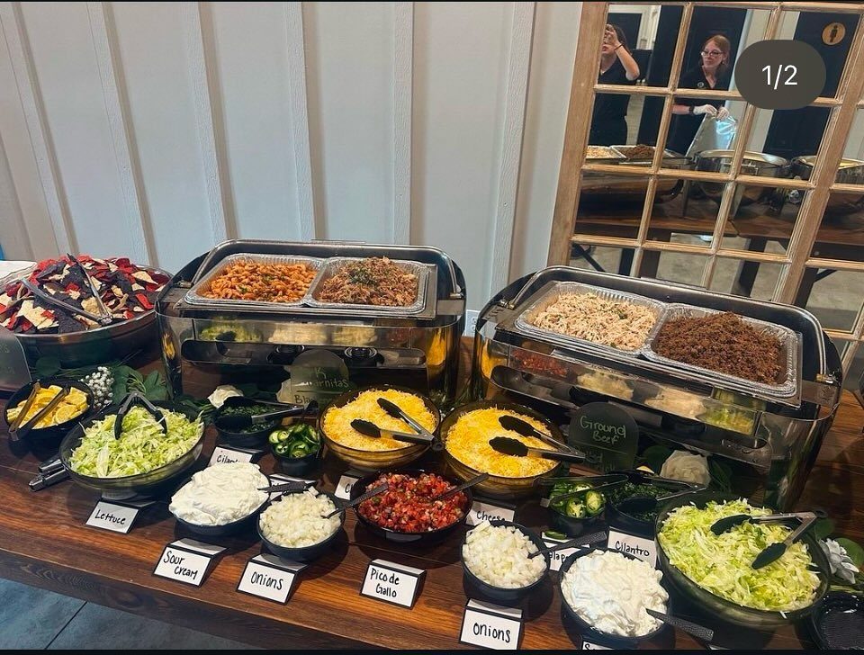 Taco fiesta buffet spread with meats in chafing dishes and various toppings in bowls