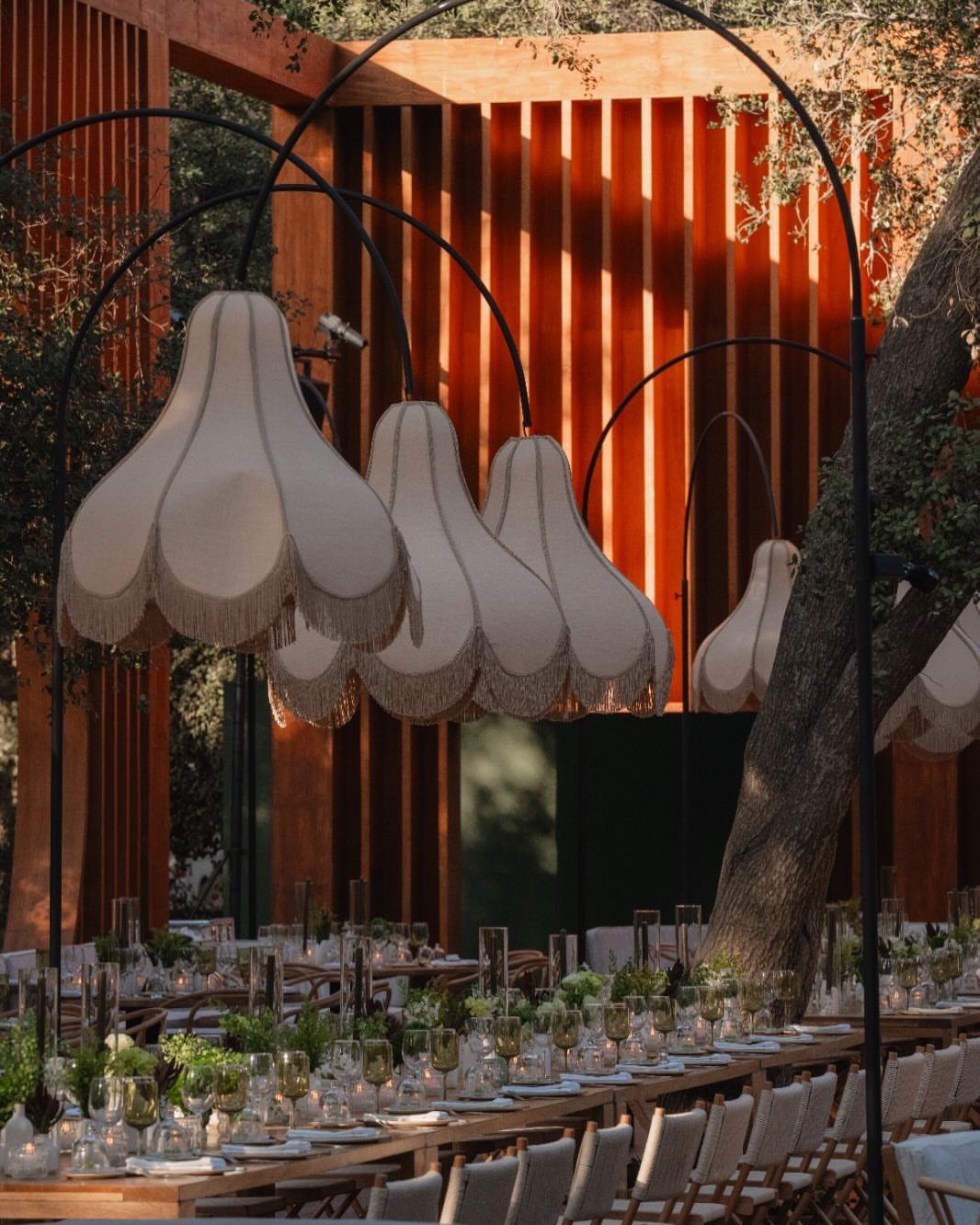Wedding Mood Board Ideas: 39 Styles from Celestial to Coastal 18 Fringed cream lampshades hanging over a long wooden wedding table with greenery.