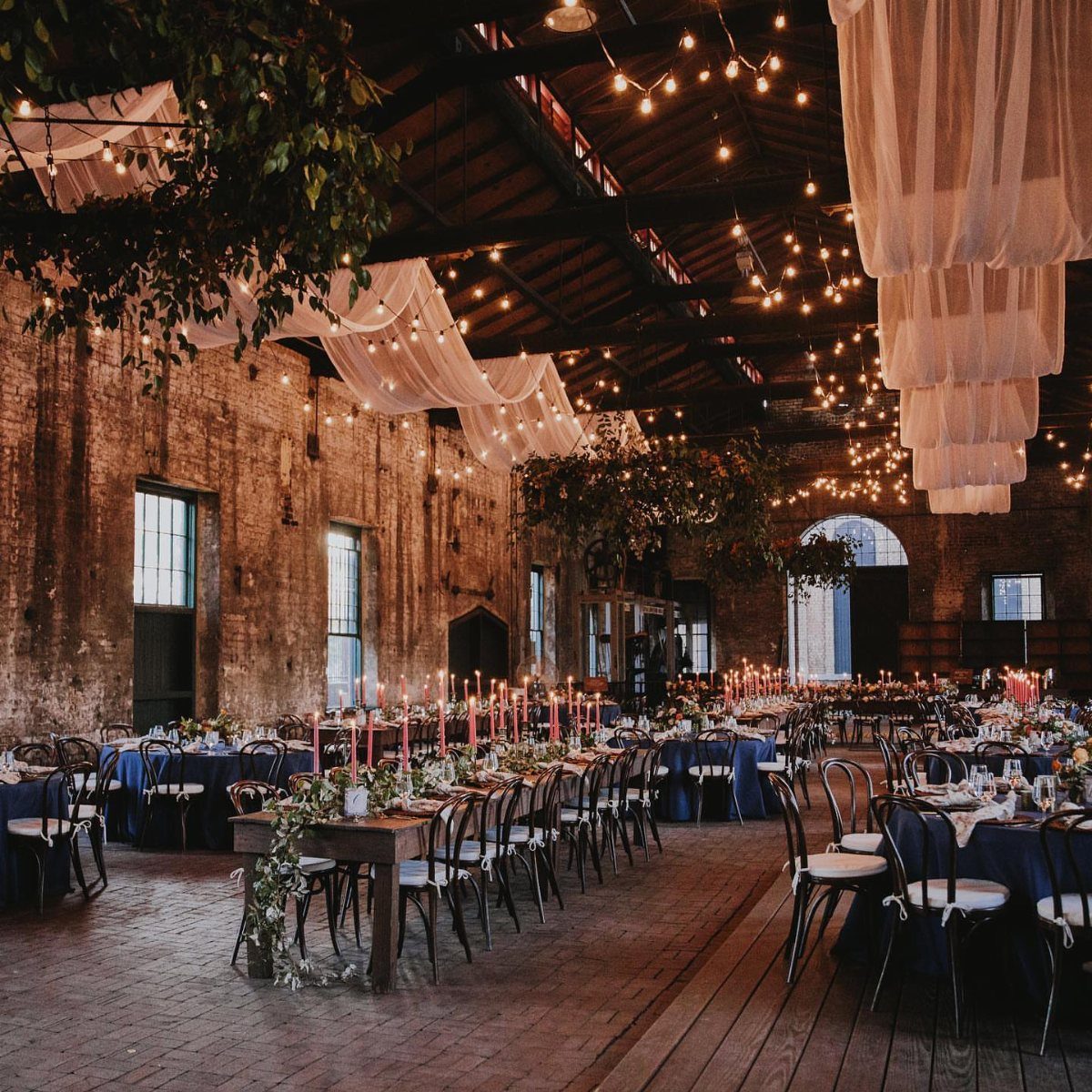Wedding Mood Board Ideas: 39 Styles from Celestial to Coastal 3 Industrial warehouse wedding venue with brick walls, white ceiling drapes, and long dining tables.