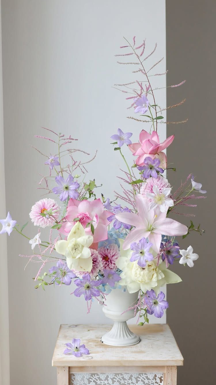 Wedding Mood Board Ideas: 39 Styles from Celestial to Coastal 40 Floral arrangement with pink lilies and purple flowers in a white pedestal vase.