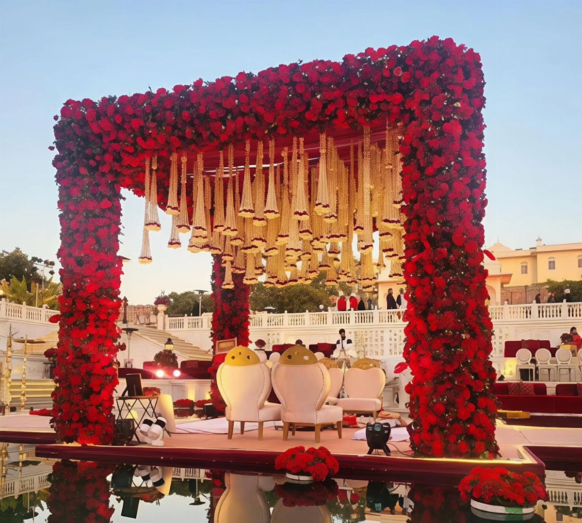 Wedding Mood Board Ideas: 39 Styles from Celestial to Coastal 17 Red rose mandap with hanging golden garlands and white chairs at an outdoor wedding