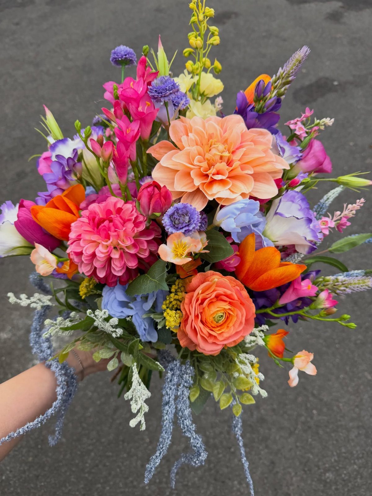 Wedding Mood Board Ideas: 39 Styles from Celestial to Coastal 11 Colorful floral bouquet with orange, pink, and blue flowers held against grey pavement.