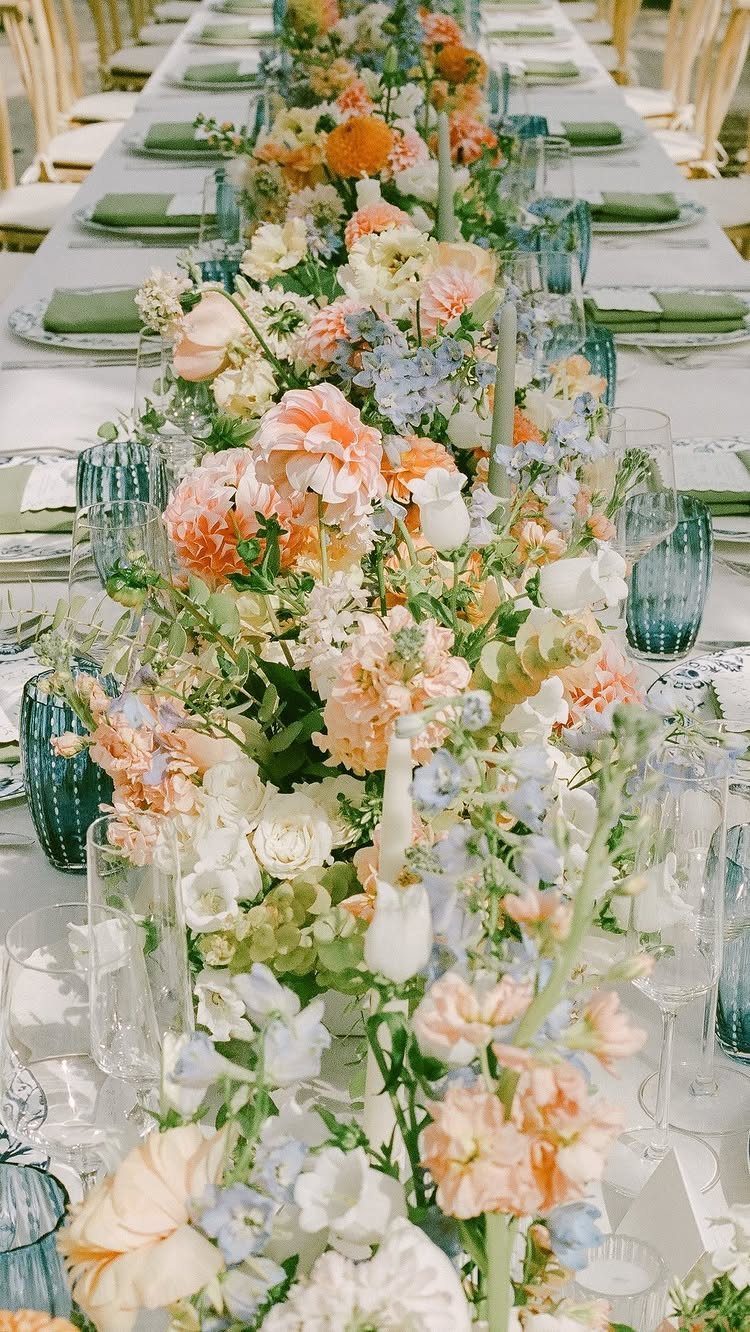 Floral table runner with peach and blue flowers and blue glassware on white linen.